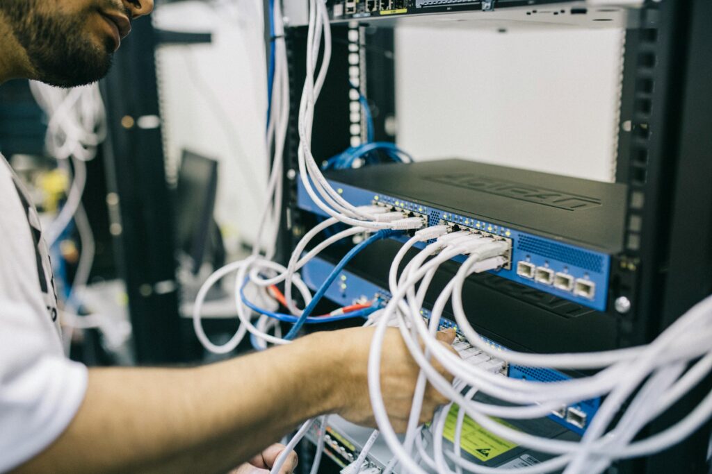 Technician working on network cabling and switches as part of NOC services.