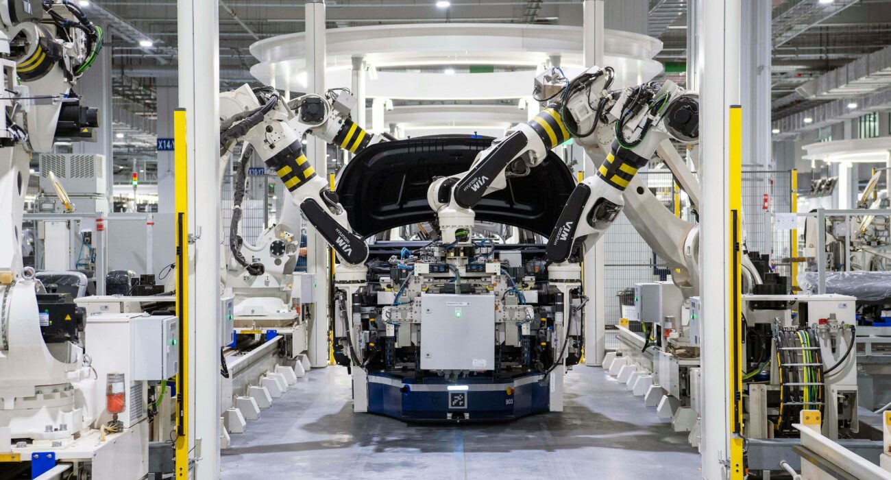 Robotic arms assembling vehicles on a modern manufacturing production line.