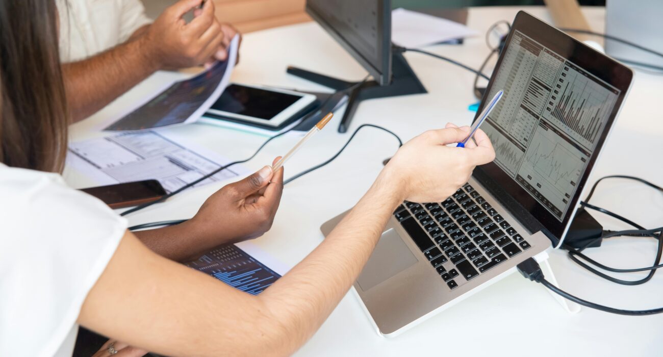 Team members reviewing charts and business data on a laptop during a cybersecurity and risk assessment meeting