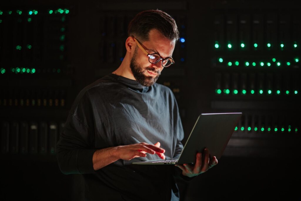 Managed IT services Pasadena technician using a laptop in a server room to monitor business network systems.