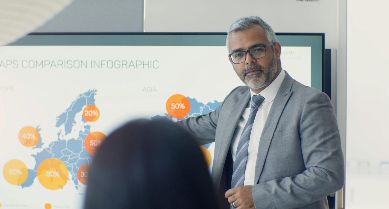 Business professional presenting data on a large screen during a privacy compliance and risk assessment meeting.