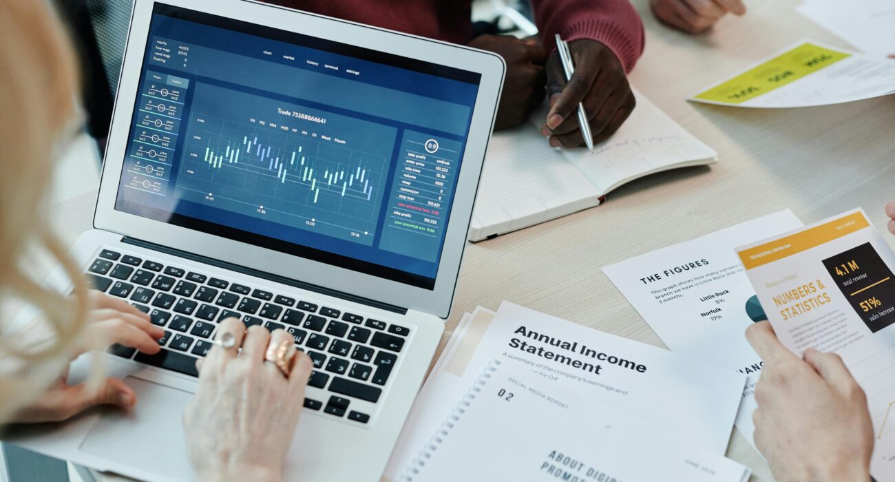 Team members review laptop data and printed reports during a Windows 11 migration planning meeting.
