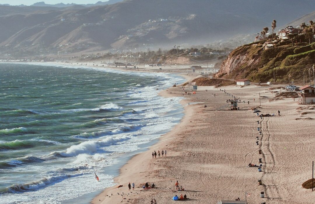 Wide view of the Malibu coastline, sandy beach, ocean waves, and surrounding hills